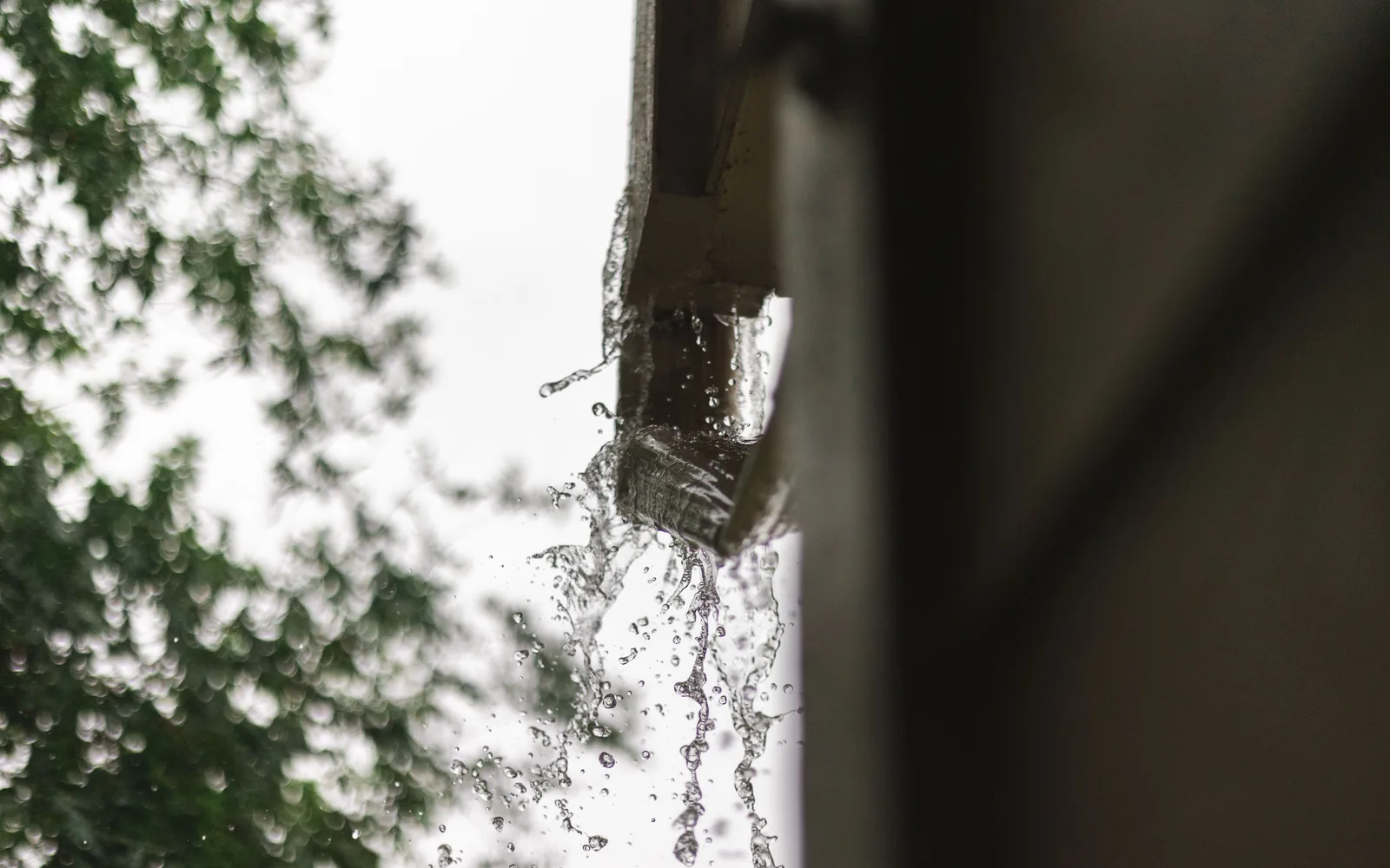 Eau débordant d'une gouttière pendant une forte pluie, illustration de dommages causés par la grêle ou la tempête