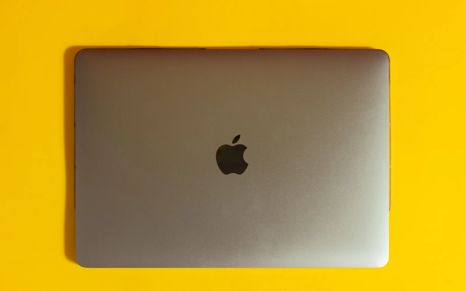 MacBook fermé posé sur un fond jaune, illustration d'un ordinateur qui ne s'allume plus pour un dossier d'assurance